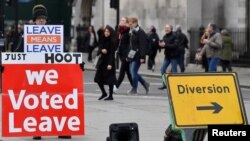 Демонстрант с плакатами "Мы голосовали за выход", "Уйти значит уйти" перед зданием британского парламента в Лондоне. Справа от него знак "Обход".