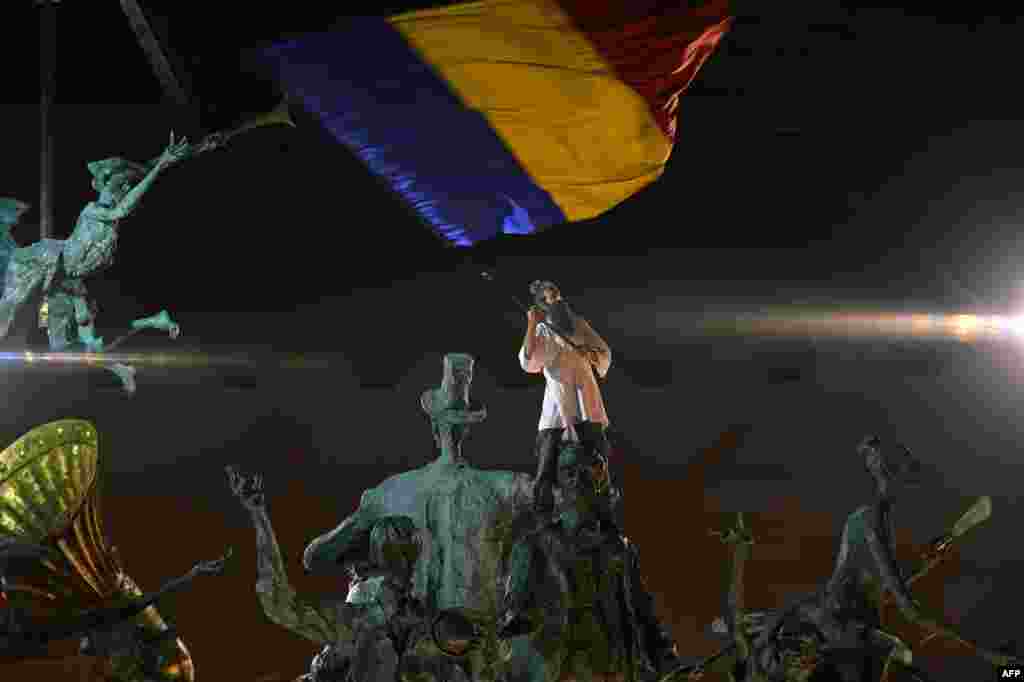 Romania -- A protester wave Romanian flag as he climbed on a monument during the fifteen day of demonstrations against the Rosia Montana Gold Corporation (RMGC), a Canadian gold mine project using cyanide, Bucharest, September 15, 2013