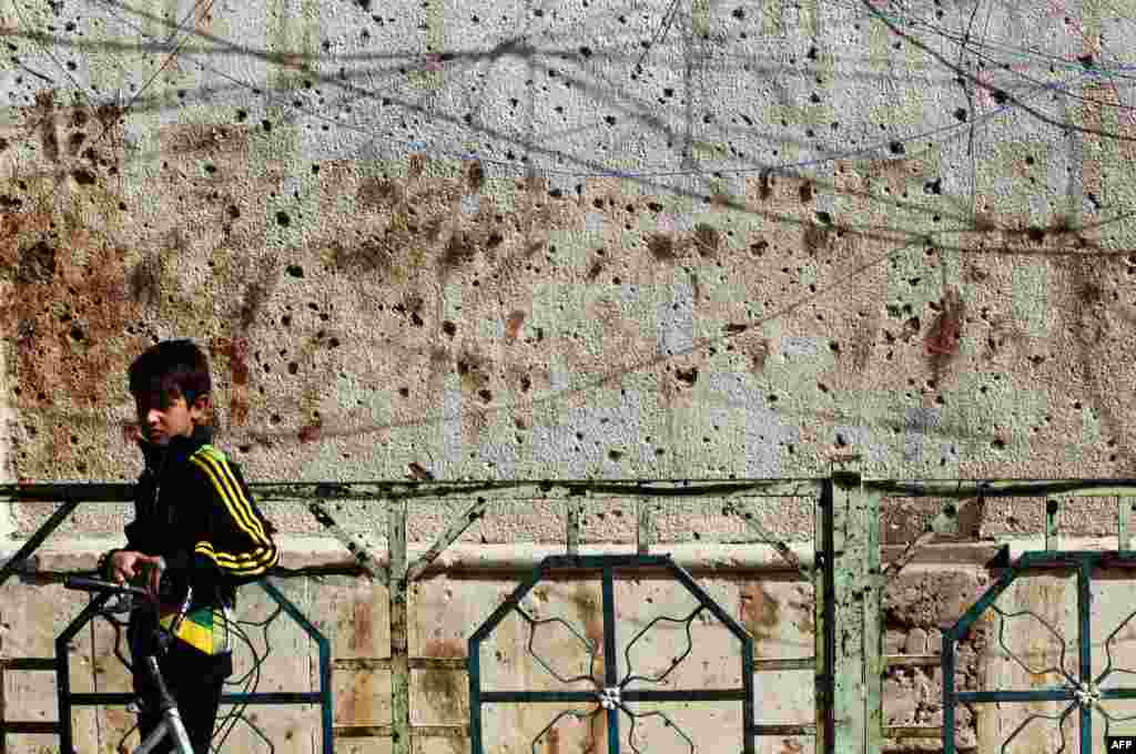 An Iraqi boy walks past a shrapnel-riddled wall of the Rasul al-Azam mosque in the Iraqi capital Baghdad. (AFP/Ahmad Al-Rubaye)