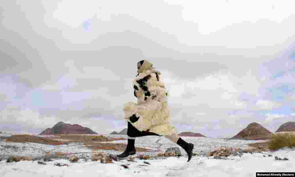 A man runs through the snow after a snowstorm in the desert near Tabuk, Saudi Arabia. (Reuters/Mohamed Alhwaity)