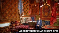 Iranian dealers sit in their booth during the 28th handmade carpet exhibition at the international exhibition complex, in Tehran, Iran, 26 August 2019