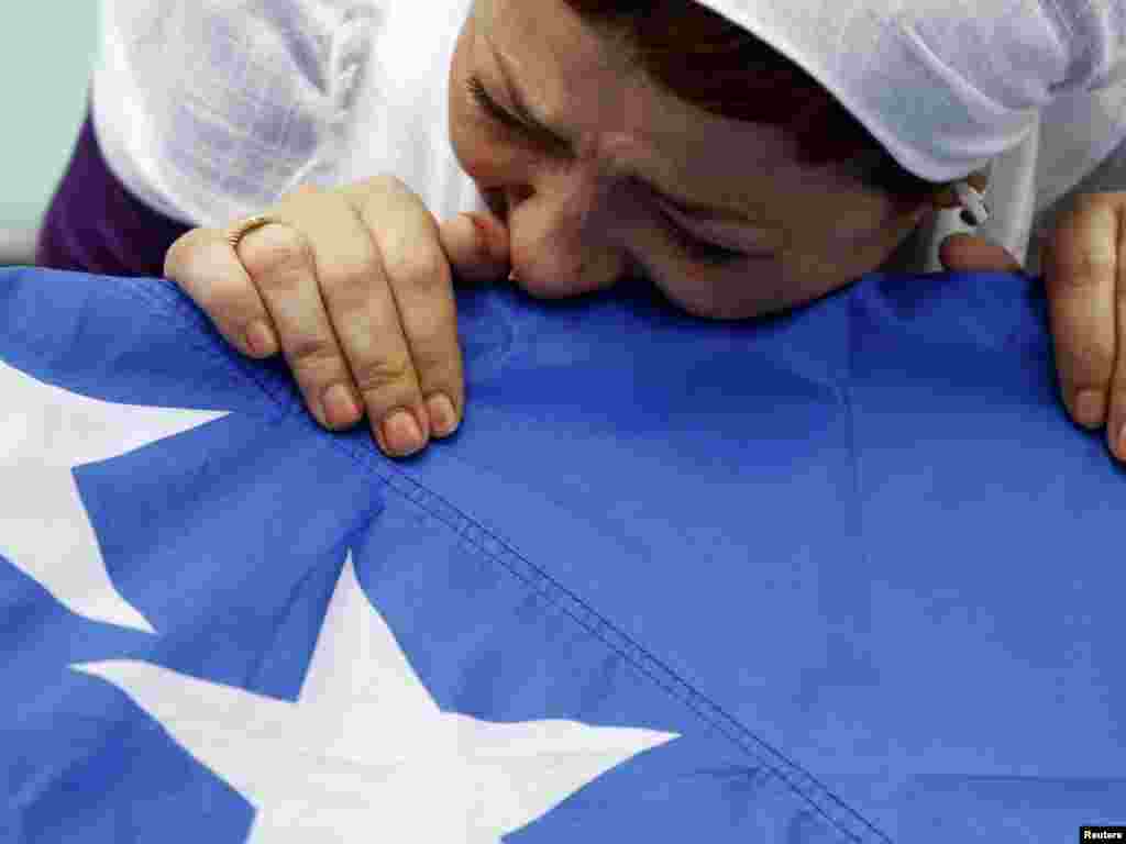 A Bosnian Muslim woman cries over a flag-draped coffin in the town of Bratunac. The remains of 31 Bosnian Muslims, killed by Serb forces during the country's 1992-95 war, were exhumed nearby and reburied in a mass funeral. Photo by Dado Ruvic for Reuters