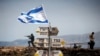 An Israeli soldier stands next to signs pointing out distances to different cities, on Mount Bental, an observation post in the Israeli-occupied Golan Heights that overlooks the Syrian side of the Quneitra crossing, May 10, 2018