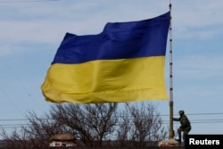 Российский военный пытается спустить украинский флаг на в/ч А2904 после того, как украинское командование потеряло контроль над ней в результате нападения вооруженных людей в российской форме в Бахчисарае, 10 марта 2014 года