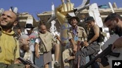 Libya -- Rebel fighters gesture as they stamp on a part of a statue of Moammar Gadhafi inside the main compound in Bab Al-Aziziya in Tripoli,23Aug2011