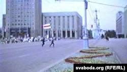 Людзі зь бел-чырвона-белым сьцягам бягуць да Дому ўраду пасьля абвяшчэньня Незалежнасьці Беларусі. 25 жніўня 1991 году