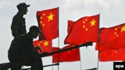 Военные на фоне китайских флагов во время антитеррористических учений стран, входящих в Шанхайскую организацию сотрудничества (ШОС).