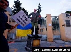 Картонная карикатура на президента РФ Владимира Путина в виде Адольфа Гитлера у посольства России в Республике Мальта. На плакате надпись по-английски: «Прекратите бомбардировку мирных жителей». Каппара, 8 марта 2022 года