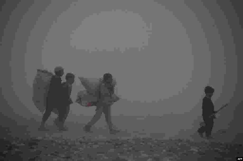 Afghan children carry bags as they walk through dense fog on the outskirts of Jalalabad. (AFP/Noorullah Shirzada)