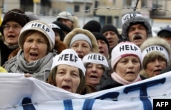 Демонстранты держат баннер со словом "Помогите", призывая остановить насилие, перед зданием офиса представительства Евросоюза в Киева. 20 января 2014 года.