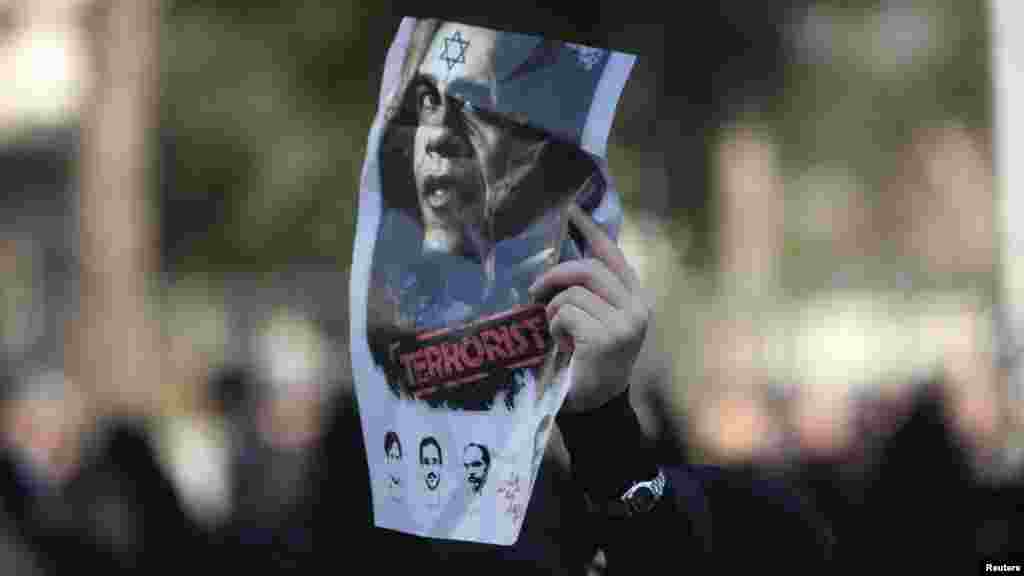 A worshipper holds an anti-U.S. poster during the funeral for nuclear scientist Mostafa Ahmadi Roshan, who was killed in a bomb blast in Tehran. (Photo by Morteza Nikoubazl for Reuters)