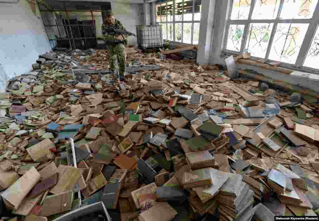 A Ukrainian serviceman inspects an abandoned library near his position on the front line in the town of Maryinka. (Reuters/Oleksandr Klymenko)