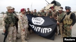 Iraqi security forces stand with an Islamic State flag which they pulled down in the city of Ramadi on February 1. The extremist group has suffered significant losses in Iraq and Syria in recent months. 