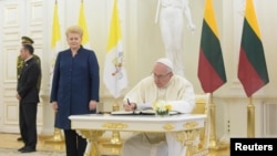 Pope Francis signs a guest book next to Lithuanian President Dalia Grybauskaite on September 22.