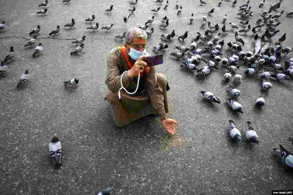 A Muslim pilgrim feeds pigeons outside the Grand Mosque in the Muslim holy city of Mecca on March 5.&nbsp;(AP/Amr Nabil)