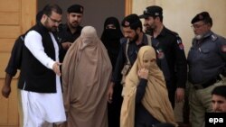 Pakistani security officials escort Afghan refugee woman Sharbat Gula (center, in burqa), after a court hearing in Peshawar on November 4.