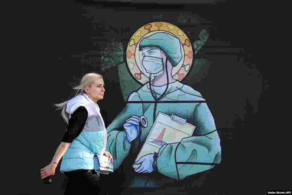 A woman walks by a depiction of medical staff wearing protective equipment, executed in the style of Orthodox icons, in Bucharest. The artwork was created by designer Wanda Hutira and is part of a campaign called Thank You Doctors, meant to raise awareness of the work of medical staff fighting the COVID-19 pandemic. Following public pressure by Romania's influential Orthodox Church, the artworks, described as "blasphemous," will be removed from all locations in the Romanian capital, according to the agency behind the project. (AP/Vadim Ghirda)