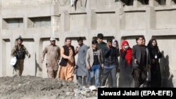FILE: An Afghan special forces soldier escorts rescued TV journalists after militants attacked Shamshad TV station in Kabul on November 7