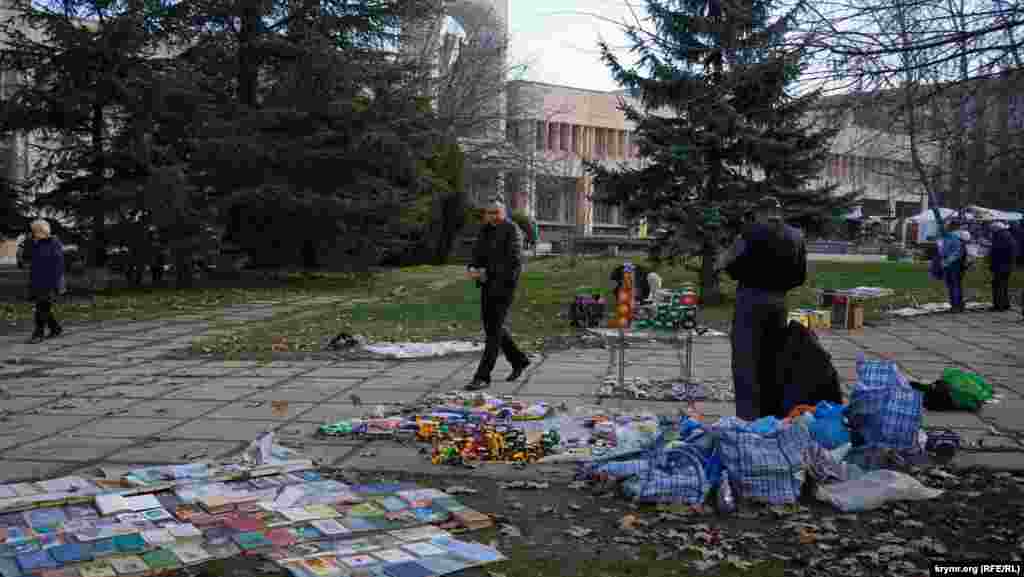 Книжково-іграшковий асортимент вздовж тротуару в сквері на вулиці Київській. Тут розпродають свої домашні бібліотеки й ті, хто готується переїхати на материк