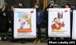 Під час акції у День святого Валентина біля Офісу президента України. На плакатах зображення керівника Офісу президента Андрія Єрмака та президентів України і Росії, Володимира Зеленського і Володимира Путіна. Київ, 14 лютого 2020 року