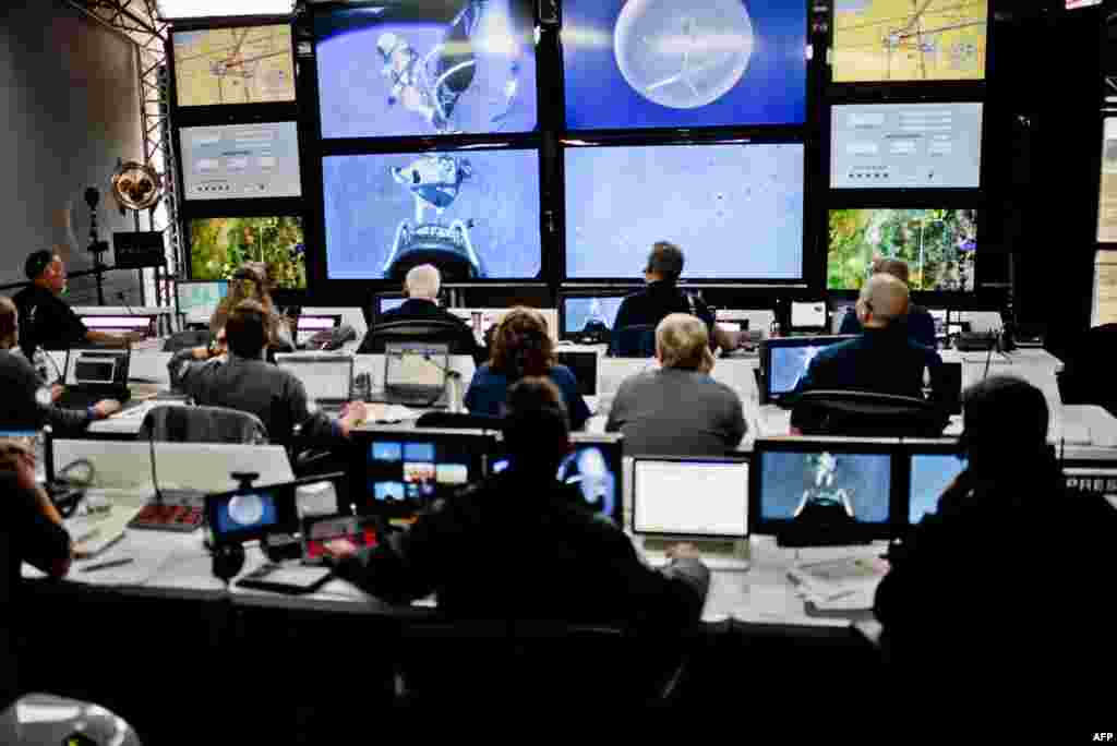 Crew members at mission control watch at the moment that Baumgartner steps off the capsule.