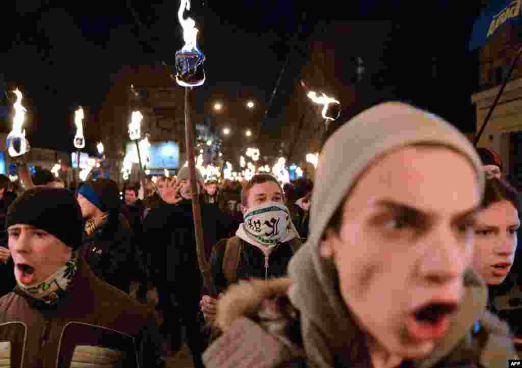 Nationalists hold torches during a march in the western Ukrainian city of Lviv on January 1, as they mark the 104th anniversary of the birth of Stepan Bandera, one of the leaders of the Ukrainian national movement. Bandera was responsible for a series of terrorist acts against Polish and Ukrainian civilians committed in interwar Poland. (AFP/Yuriy Dyachyshyn)