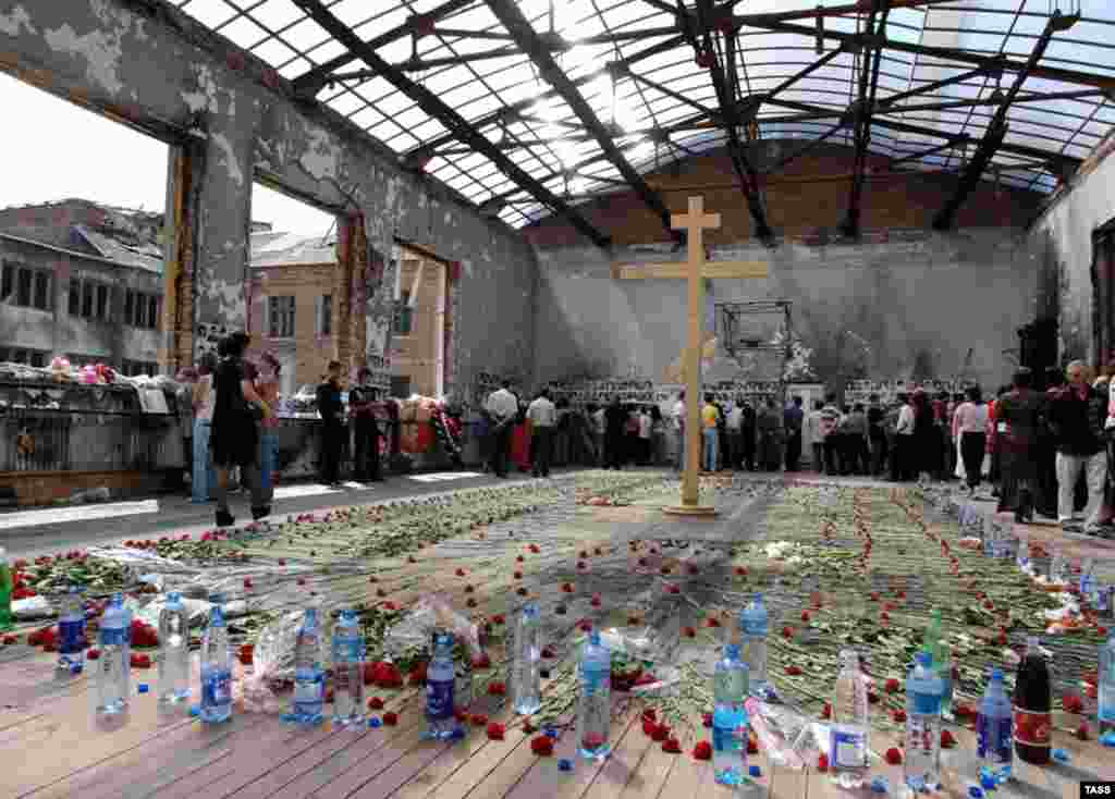 A memorial service in the ruined gymnasium of Beslan School No. 1 on September 1, 2006 (TASS) - Together with survivors, a number of independent investigators and journalists have denounced what they say was a botched-up rescue operation. Yury Savelyev, an explosives expert and State Duma deputy, published a report confirming the battle was triggered by soldiers firing grenades from a building across from the school.