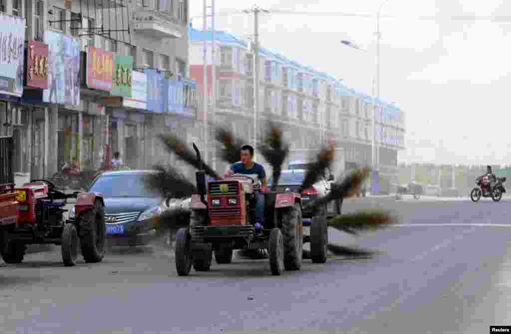 A man drives an improvised tractor with 12 brooms tied to the back, as he tries to clean a road in Mohe in China's Heilongjiang Province. (Reuters)