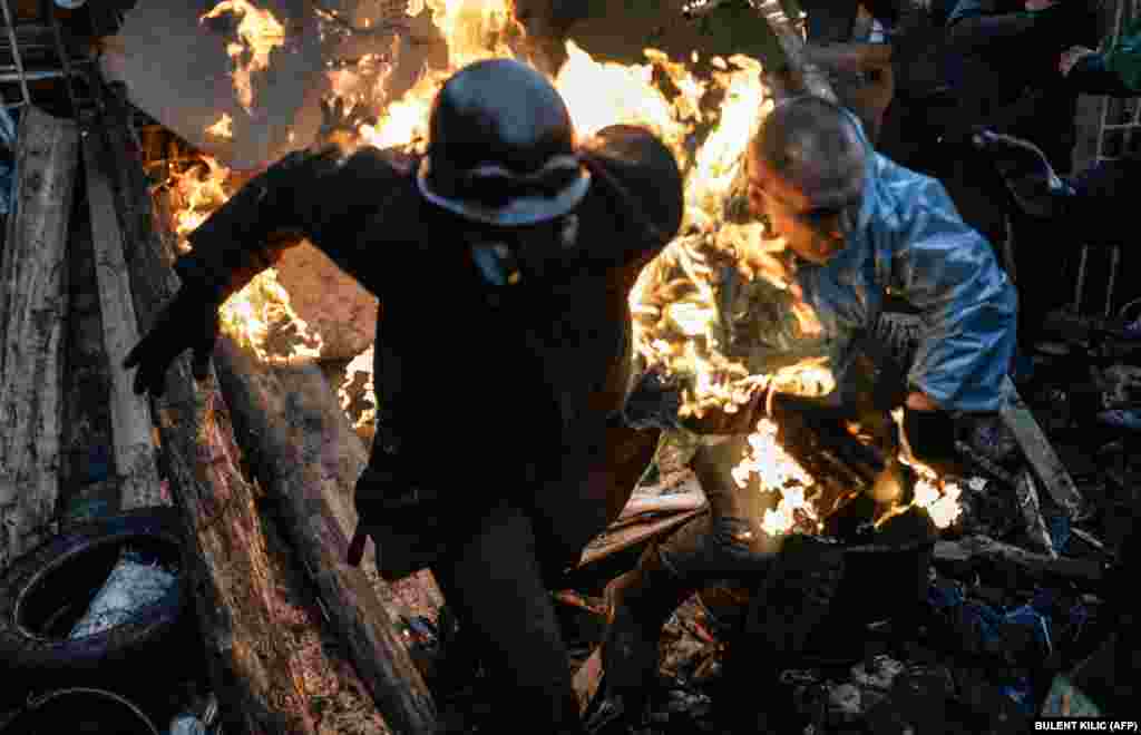 Protesters catch fire as they stand behind burning barricades.