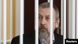 Former opposition presidential candidate Andrey Sannikau sits in a cage during a court hearing in Minsk in April.