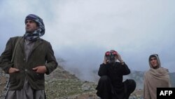 Afghanistan -- An Afghan villager (C) looks through binoculars at the mountains where an Afghan Pamir Airways plane is believed to have crashed in the Salang pass, north of Kabul, 17May2010