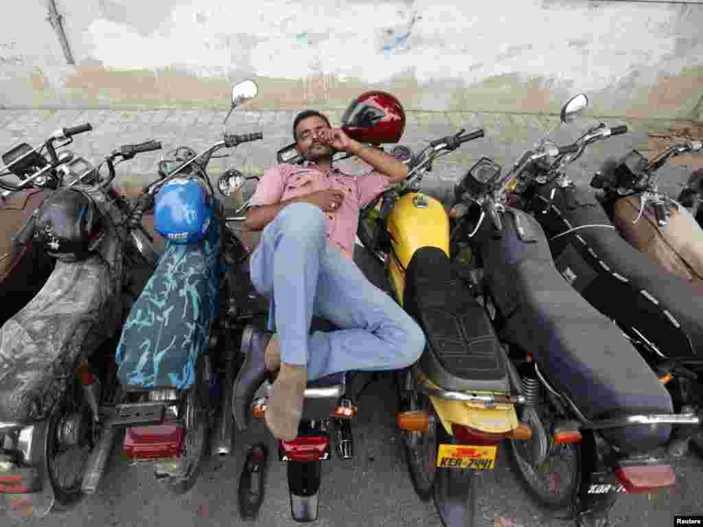 A man takes a nap on a motorbike outside a post office in Karachi.Photo by Athar Hussain for Reuters