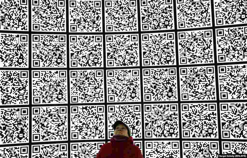 A woman looks at a wall full of QR codes in a park next to the Kremlin and Red Square in Moscow. (epa-EFE/Sergei Ilnitsky)&nbsp;