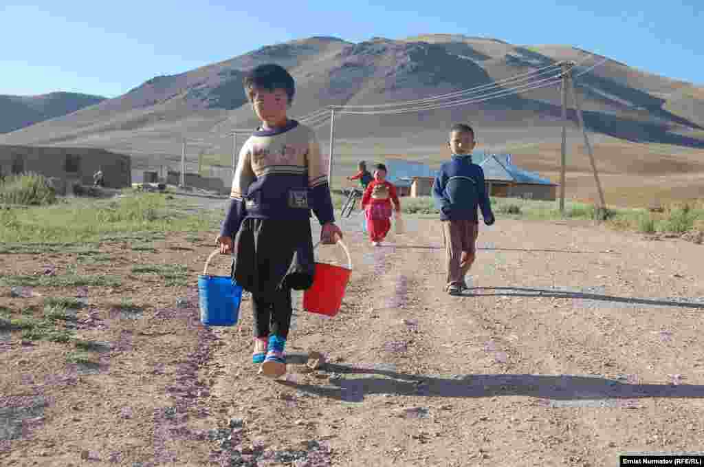 Киргизия. Дети несут воду в пластиковых ведрах и бутылках