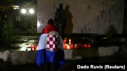 Muškarac sa zastavom "Herceg-Bosne" pali svijeću i odaje počast Slobodanu Praljku, Mostar