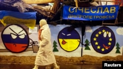 A pro-EU protester walks by a barricade decorated with murals during a rally at Independence Square in Kyiv on December 17.