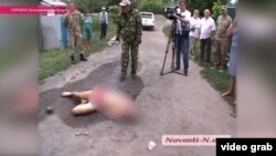 Local residents surround the body of Aleksandr Tsukerman in the middle of a dirt road in the southern village of Krivoye Ozero.