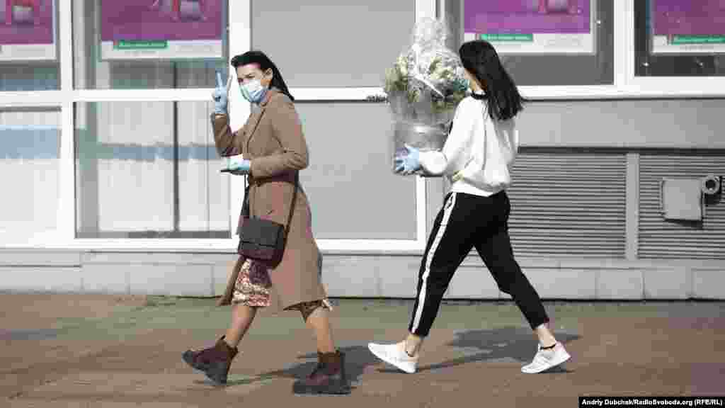 Дівчата у медичних масках та з букетом квітів неподалік від станції метро Мінська