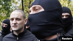 Сергей Удальцов в сопровождении бойцов спецназа