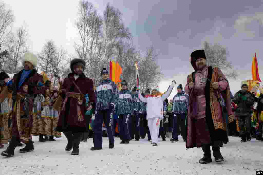 Olympic torchbearer Akhmetova Svetlana (center) waves as she holds the torch with the Olympic flame in Irkutsk on November 23. Russia is hosting the 2014 Winter Olympics in the Caucasus city of Sochi. (AFP)