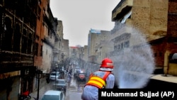 A volunteer sprays disinfectant in an effort to curb the spread of the coronavirus outbreak in Peshawar on March 23.