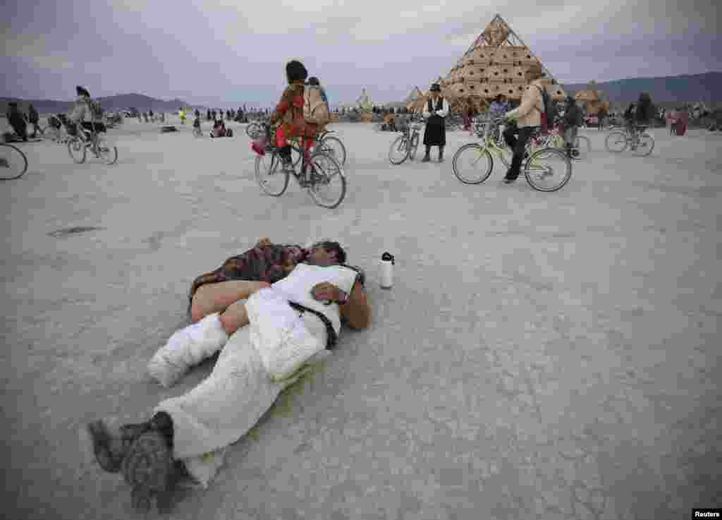 Participants cuddle at sunrise at the "Temple of Whollyness" during the Burning Man 2013 arts and music festival in the Black Rock Desert of Nevada.