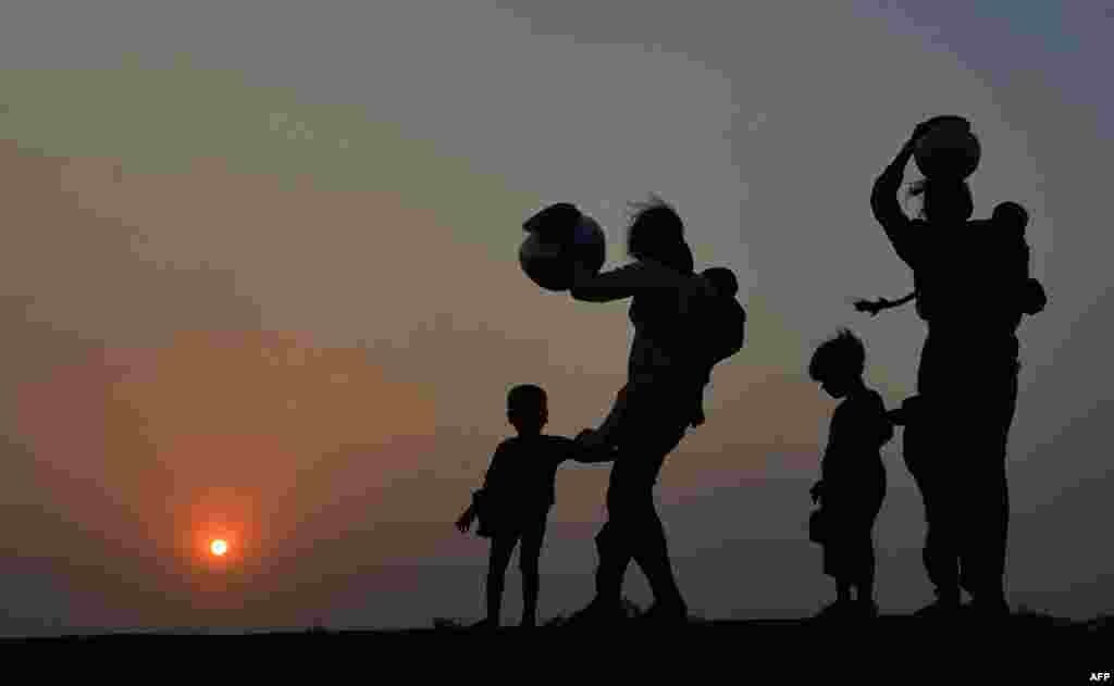 Pakistani residents carry water pots along the banks of the Ravi River on the outskirts of Lahore. (AFP/Arif Ali)