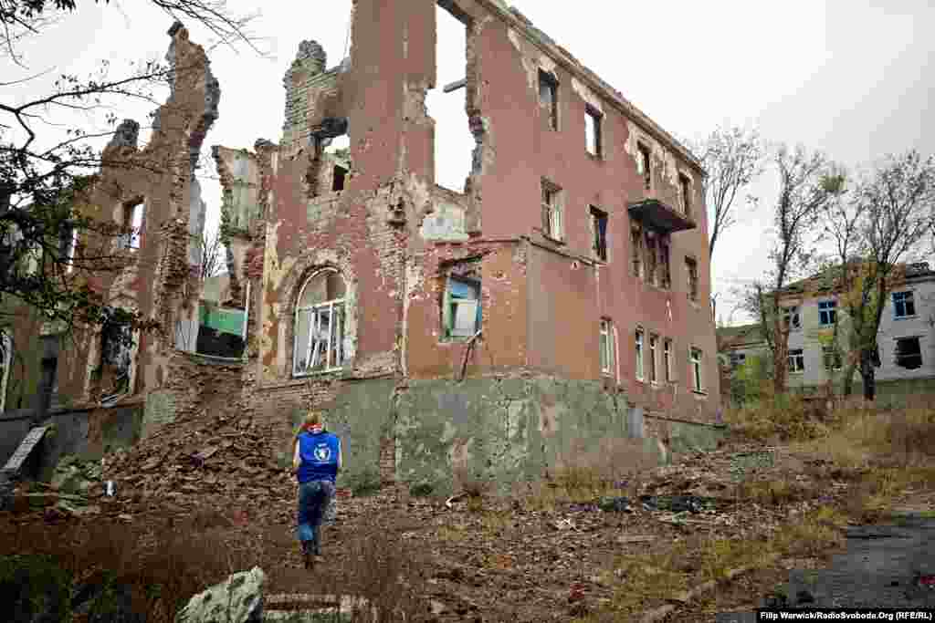 Представитель Всемирной продовольственной программы стоит рядом с разрушенным зданием в Славянске.