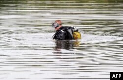 Un scafandru caut^cutiile negre la locul accidentului.