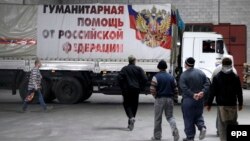 Люди направляются к грузовой машине, на которой надпись: "Гуманитарная помощь от России". Иллюстративное фото.