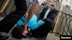 A Pussy Riot supporter is detained by security guards on the steps of the cathedral.