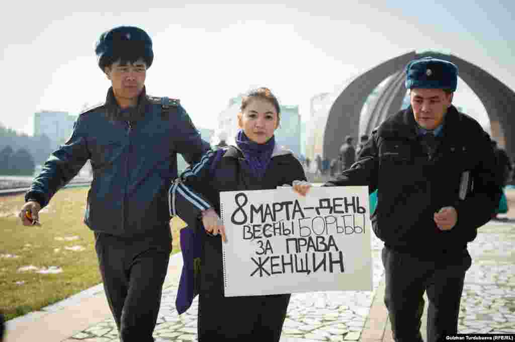 A participant in a rally to mark International Women&#39;s Day on March 8 is led away by police after the rally was attacked by masked men. Dozens of protesters were detained by police -- allegedly for their own protection -- while three suspected hooligans were also detained. (RFE/RL/Gulzhan Turbubaeva)