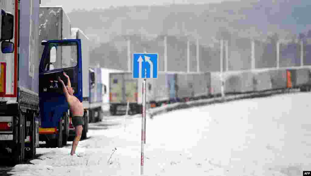 A truck driver does his morning exercises as his vehicle stands in line at the Belarusian-Lithuanian border, some 150 kilometers northwest of Minsk. (AFP/Yasin Akgul)