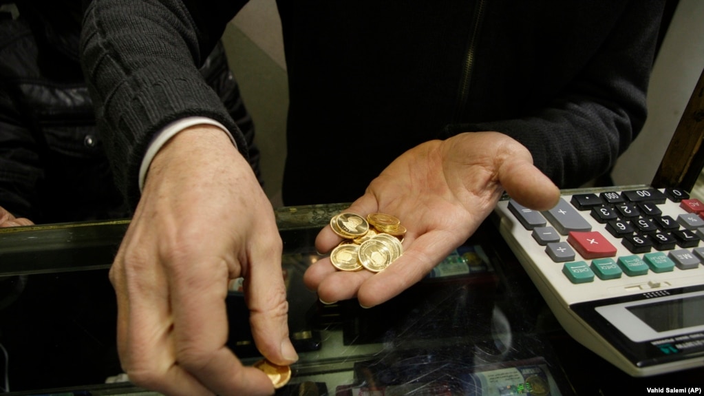 An Iranian goldsmith counts his gold coins at a gold market in the main old Bazaar of Tehran.